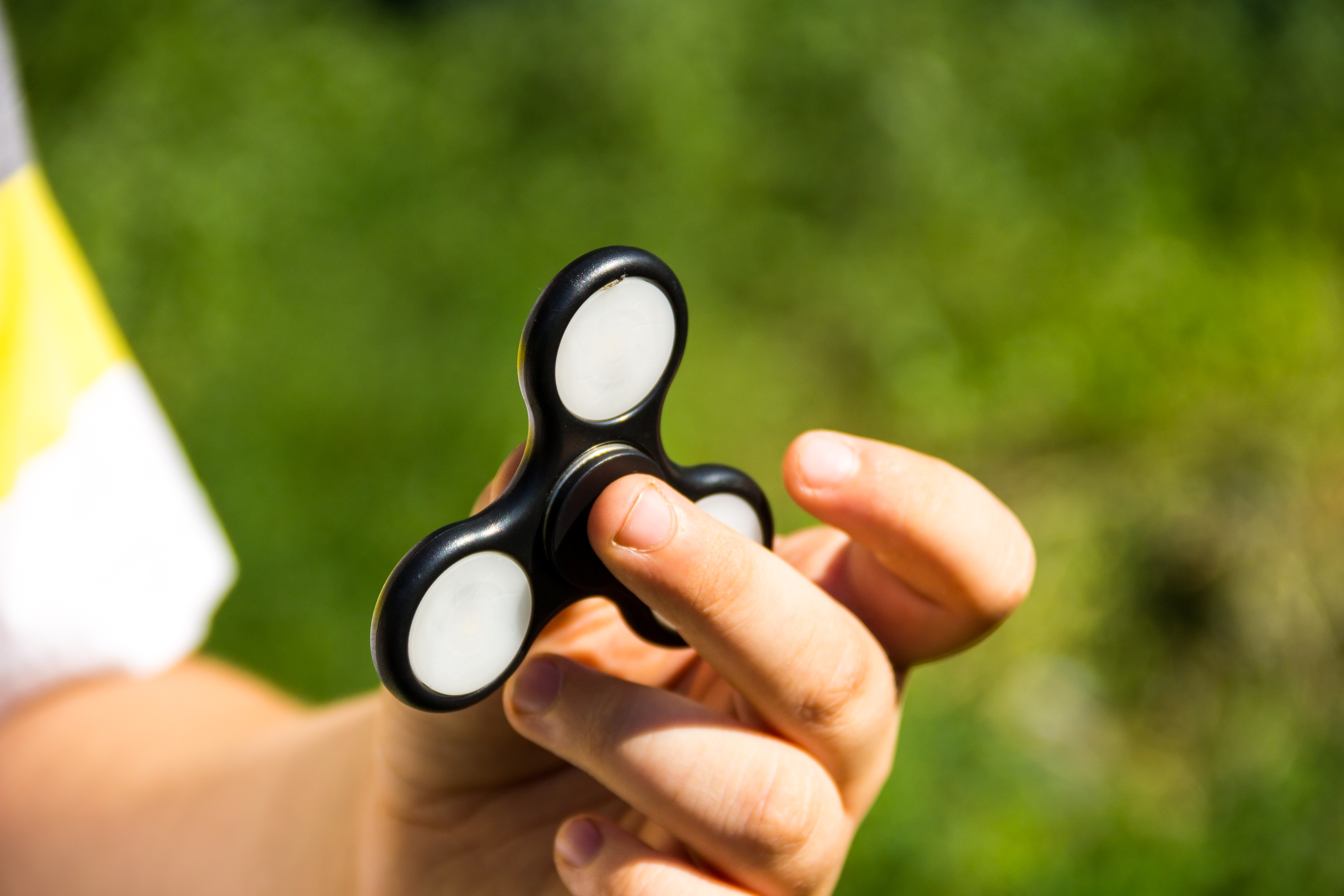 Boy playing with fidget spinner stress relieving toy outdoor